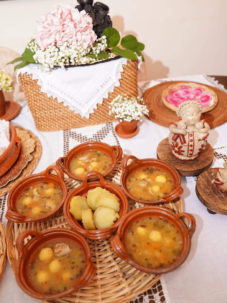 Mesa festiva con canasta de hortensias y platos de sopa, en un ambiente acogedor y familiar.
