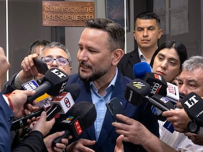 Derlis León, con traje oscuro, responde preguntas de periodistas en un evento con cartel de 'COMISION DE PRESUPUESTO' al fondo.