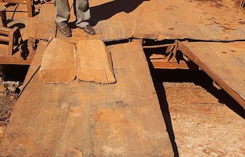 Rampa de metal oxidado con bloques de madera en el centro, sobre terreno de tierra y rocas, sin personas visibles.