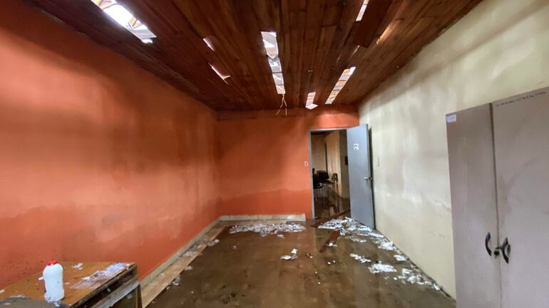 Habitación con paredes naranjas y suelo inundado, sin personas visibles, con muebles en estado de abandono.