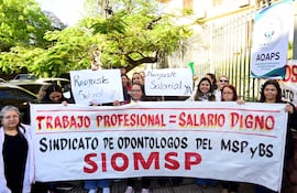 Mujeres sosteniendo carteles en manifestación; un banner grande muestra 'TRABAJO PROFESIONAL = SALARIO DIGNO'.