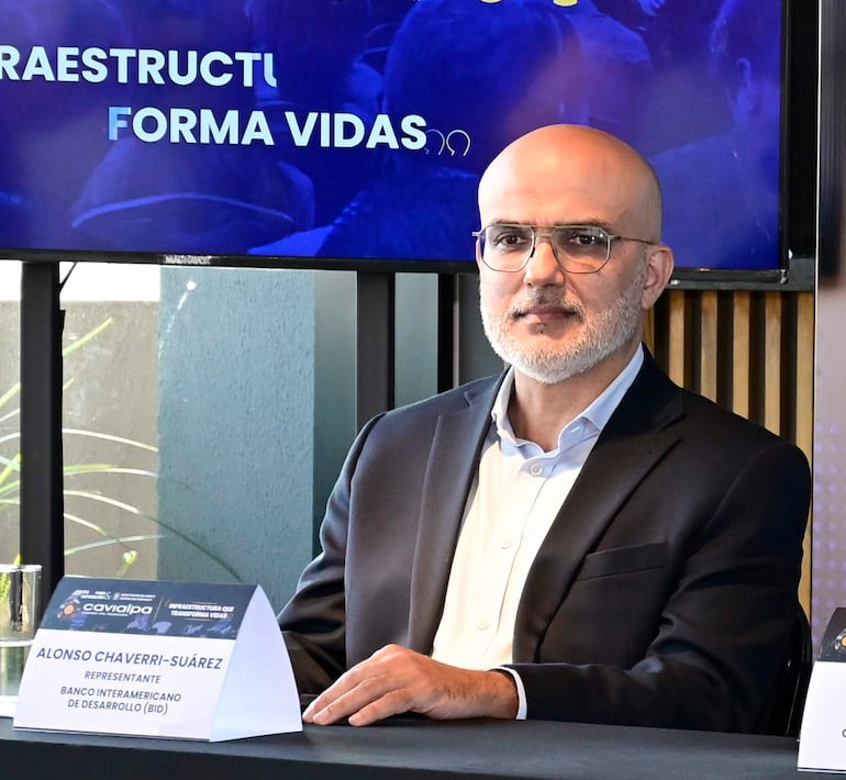 Alonso Chaverri-Suárez, con cabello canoso y gafas, viste blazer oscuro y camisa clara, sentado ante un micrófono en un ambiente formal.