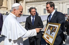 El papa León XIV sonríe y señala mientras Asinelli y Boto lo observan, vestidos con trajes oscuros y corbatas.