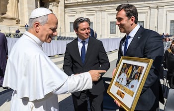 El papa León XIV sonríe y señala mientras Asinelli y Boto lo observan, vestidos con trajes oscuros y corbatas.