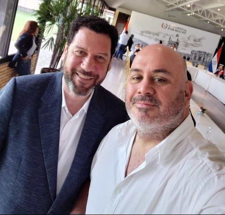 Jorge Salvador Cappello sonríe con saco oscuro y barba, junto a Turi Capello, ambos con camisas blancas en ambiente oficial.