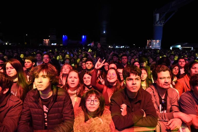 Jóvenes en concierto, levantando las manos y sonriendo en medio de luces de colores, con expresiones de alegría y tranquilidad.