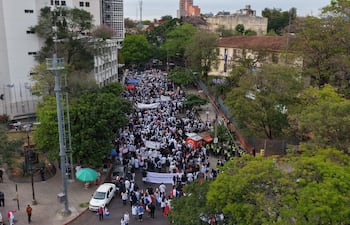 Multitud de médicos con pancartas y banderas, vestidos en su mayoría con tonos claros, durante la manifestación en la calle.