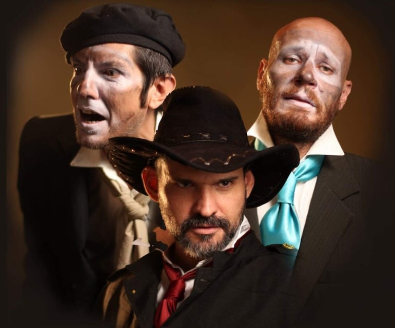 Tres hombres en retrato: uno con rostro pintado y gorro negro, otro serio con sombrero negro y corbata roja, y uno desolado con chaqueta y corbata azul.