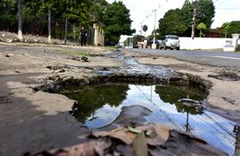 Del pozo repleto de agua servida, en una vereda de Lambaré, sobresalen varillas. Esto convierte al sitio en una trampa para los peatones.