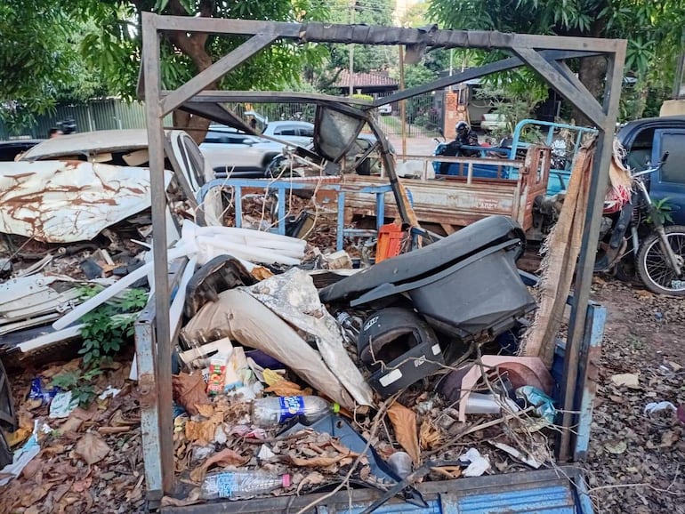 Vista de vehículos abandonados y escombros en un área descuidada de la Comisaría 10, rodeada de vegetación densa.