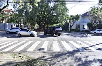 Intersección de calles con varios vehículos, incluyendo un automóvil blanco y un SUV negro, sin presencia de personas.