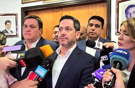 Cesar Sosa con saco oscuro y camisa clara, mientras Raúl Latorre sostiene micrófono, rodeados de periodistas en un salón.