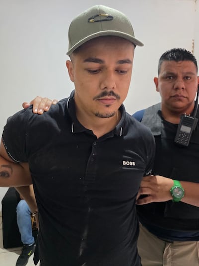 Patrick Fernandes de Oliveira (33), custodiado por un agente policial tras su detención.