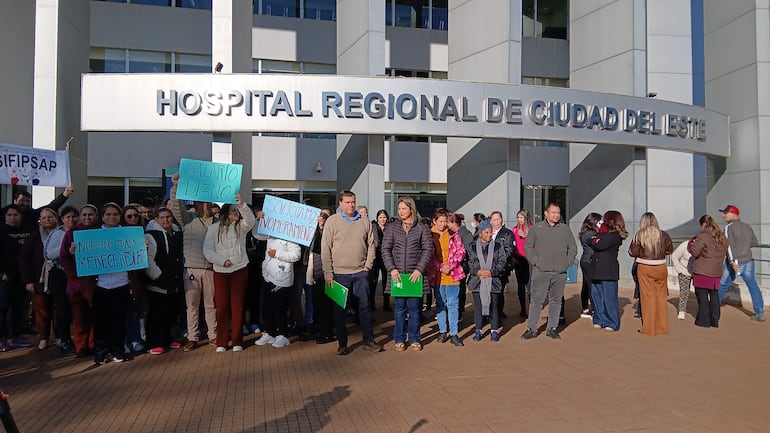 Manifiesto de funcionarios del IPS con carteles en apoyo a salarios dignos, frente a un moderno edificio del hospital.