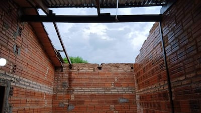 Interior de cocina en construcción con paredes de ladrillo expuestas y cielo nublado arriba.