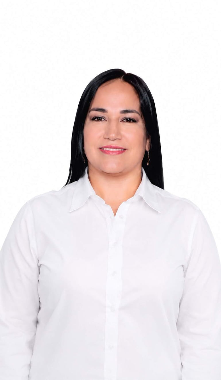 Susana Verza sonríe, vistiendo una camisa de manga larga, con un ambiente festivo alrededor.