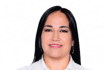 Susana Verza sonríe, vistiendo una camisa de manga larga, con un ambiente festivo alrededor.