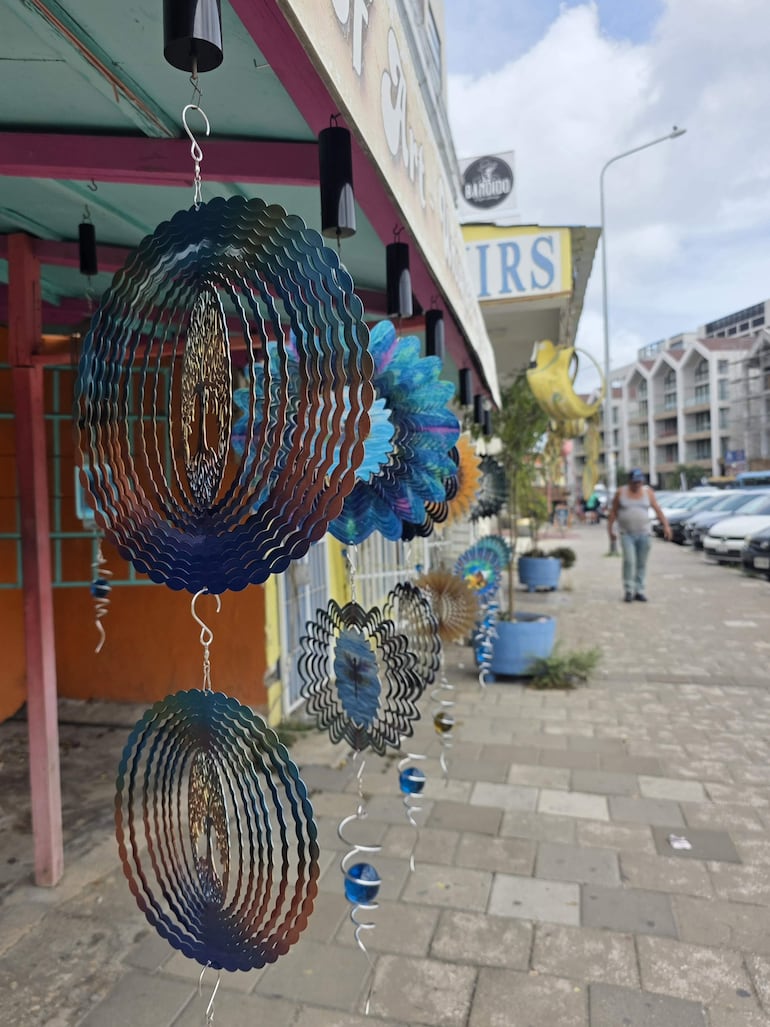 Decoraciones en espiral de colores brillantes colgadas en un marco de madera en un entorno urbano de Willemstad.