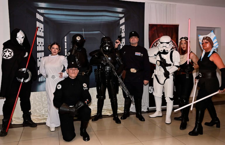 Seis personas disfrazadas de 'Star Wars' posando, con sables de luz y vestimentas de varias franquicias de la saga.