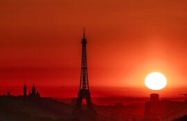 El sol sale junto a la Torre Eiffel y la Basílica del Sagrado Corazón en lo alto de la colina de Montmartre, en París, el 1 de julio de 2025, mientras la ciudad se encuentra en alerta roja por altas temperaturas. La cima de la Torre Eiffel fue cerrada, se prohibió el tráfico contaminante y se impusieron restricciones de velocidad debido a la ola de calor que azota Europa.
