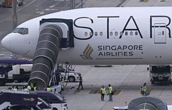 Oficiales se reúnen alrededor del avión de Singapore Airlines, un Boeing 777-300ER, estacionado en el aeropuerto internacional Suvarnabhumi en Bangkok.