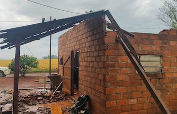 Construcción de ladrillo con parte del techo derrumbado, rodeada de escombros en un entorno rural.