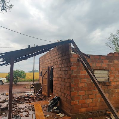 Construcción de ladrillo con parte del techo derrumbado, rodeada de escombros en un entorno rural.