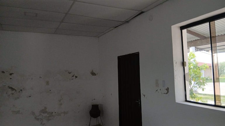 Espacio interior con paredes desgastadas y puerta negra, sin personas visibles ni elementos que indiquen actividad.