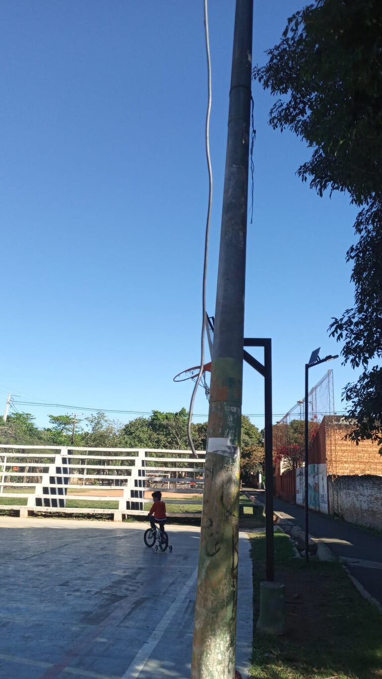 Un niño andando en bicicleta en la plaza donde se observa un cable suelto.