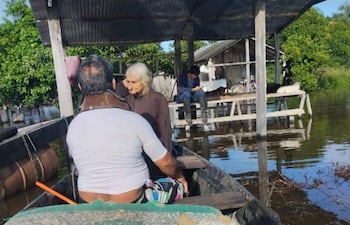 Un hombre en bote ayuda a una mujer cuya vivienda fue tomada por las aguas.