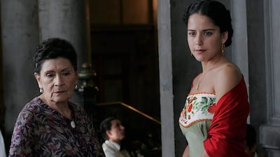 Mujer con vestido de noche observa una proyección en un ambiente elegante, transmitiendo tranquilidad.