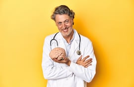 Doctor sostiene un modelo de cerebro en la mano.