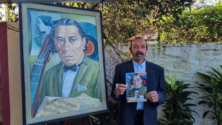 Gil Alegre en chaqué oscuro con camisa clara, sosteniendo una revista frente a un retrato de músico en un entorno con vegetación.