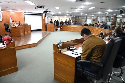 Miguel Sosa y Arturo Almirón Tuki en la mesa, vestidos formalmente, mientras un grupo los observa en un recinto legislativo.