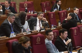 Luis Federico Franco Alfaro en el centro, con expresión pensativa, rodeado de otros asistentes en un espacio legislativo formal.