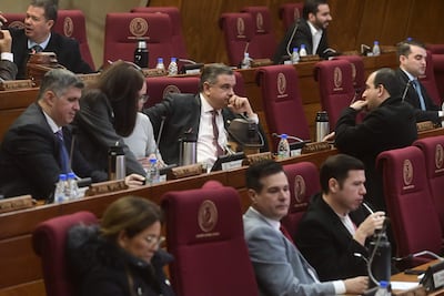 Luis Federico Franco Alfaro en el centro, con expresión pensativa, rodeado de otros asistentes en un espacio legislativo formal.