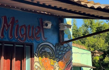 Fachada de un edificio con mural colorido de un ángel y cámaras de vigilancia visibles en la pared.