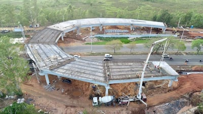 Varios trabajadores con cascos y chalecos reflectantes en obra del viaducto, con camión vertiendo concreto en el fondo.