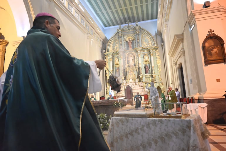 Sacerdote en ornamento verde con incensario humeante en altar decorado, rodeado de otros religiosos en un ambiente solemne.
