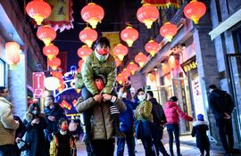 Personas con mascarillas caminan por la calle Qianmen en Beijing el 11 de febrero de 2021, antes del Año Nuevo Lunar, que marca el comienzo del Año del Buey el 12 de febrero.