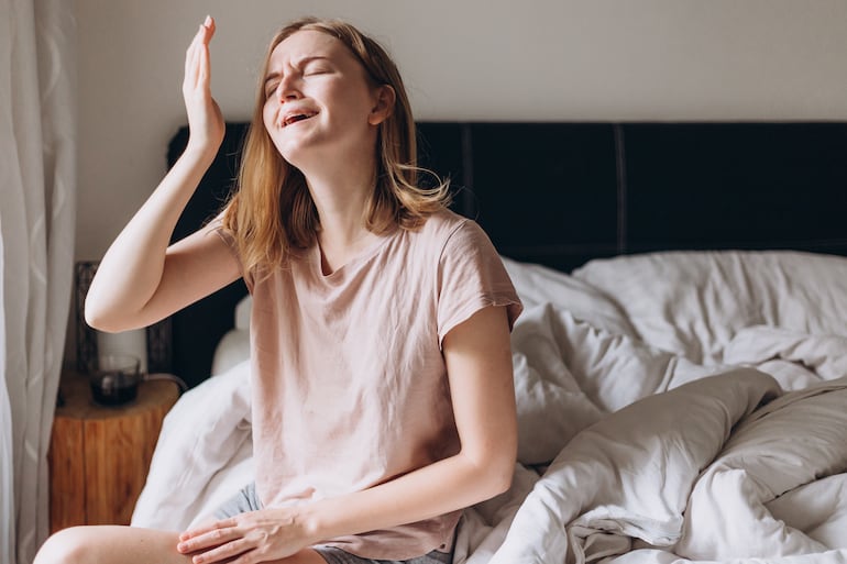 Mujer llora en su cama.