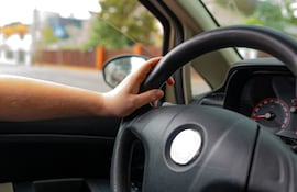 Una persona con las manos al volante.
