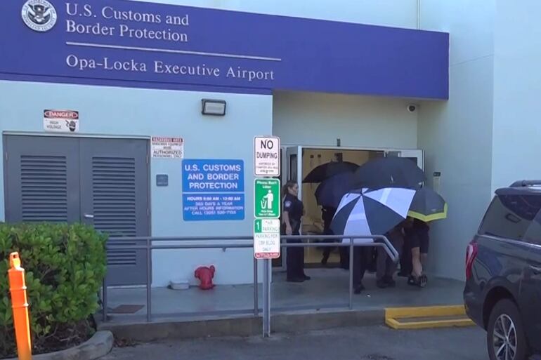 Captura de video que muestra a personas cubriendo con sombrillas al excandidato presidencial brasileño Flávio Bolsonaro a su llegada este miércoles al Aeropuerto Ejecutivo de Miami-Opa Locka en Miami (EE.UU.). 