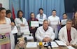Médicos en batas y gestos serios sostienen carteles con la frase 'YO RENUNCIO' en un consultorio médico.