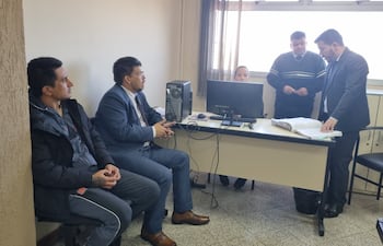 Dionisio Manuel Cáceres Cabrera, esposada y sentado (i), junto con su abogado defensor David González, ante el juez Rodrigo Estigarribia, durante al audiencia de imposición de medidas.