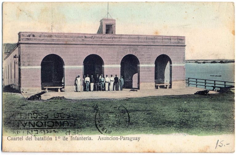 Soldados uniformados alineados frente al cuartel con césped verde y edificio de piedra clara al fondo.