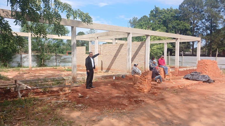 Jorge Servín señalando un punto en la obra, rodeado de hombres en ropa de trabajo, en un ambiente de construcción soleado.