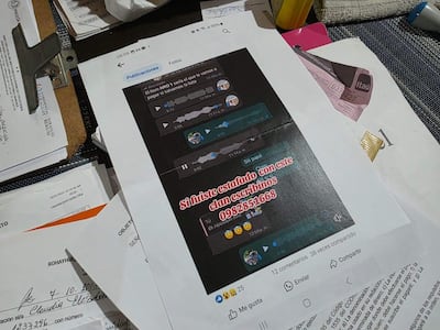 Documentos desordenados sobre una superficie, incluyendo hojas impresas y capturas de conversaciones sobre estafas.