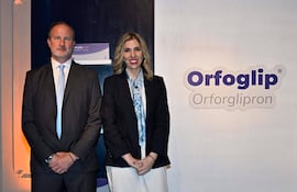 Dos personas en ambiente moderno: hombre con traje oscuro y mujer con blazer negro, ambos sonrientes ante el logotipo de Orfoglip.