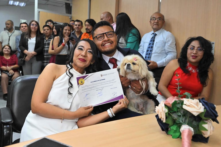 Andrés Alquinga y Diana Tupiza muestran el certificado simbólico de matrimonio con la “firma” de su mascota Luna después de la boda, en la oficina del Registro Civil Central de Quito, el 7 de julio de 2026.